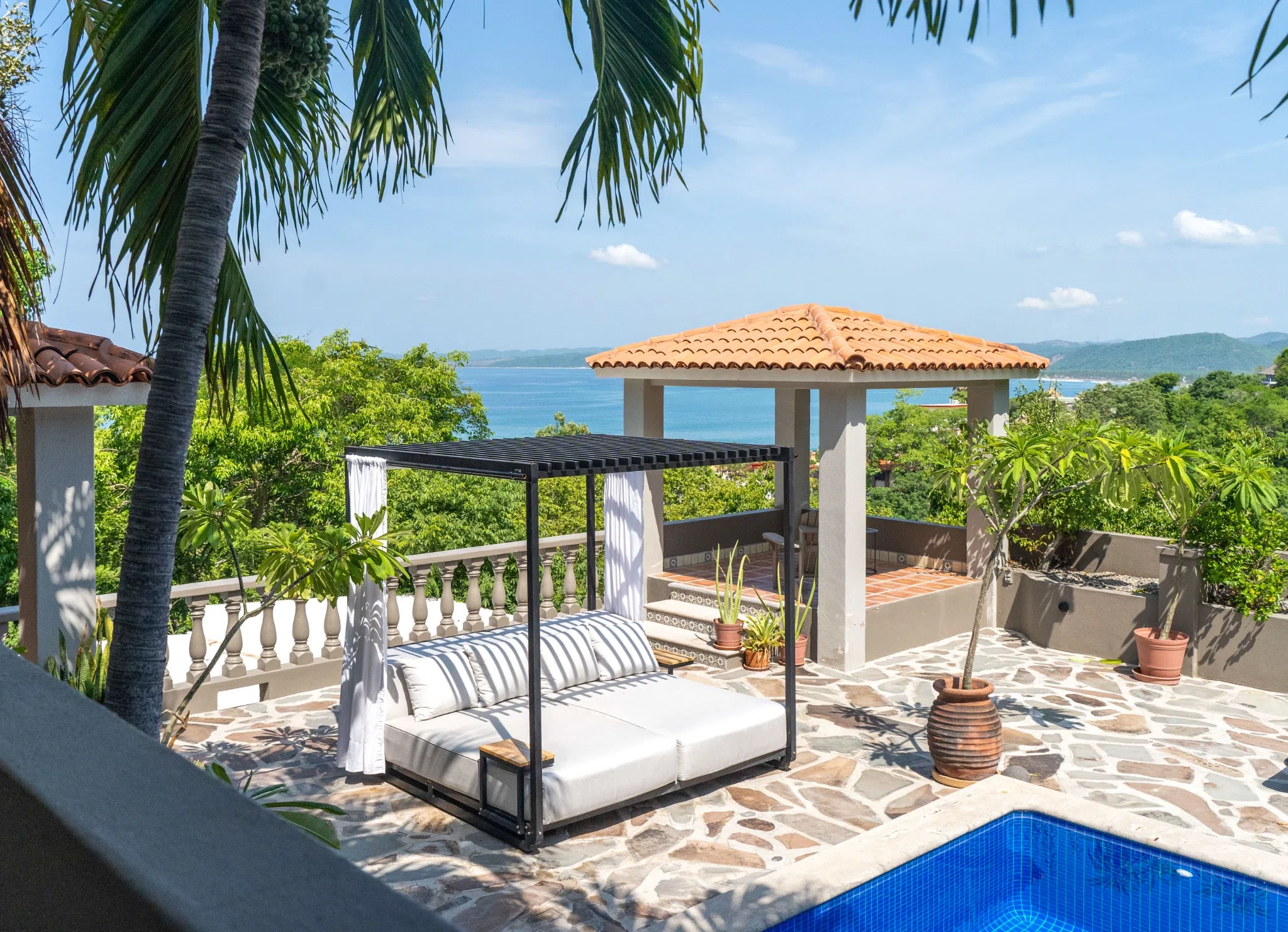 Poolside daybed framed by palms and an ocean view