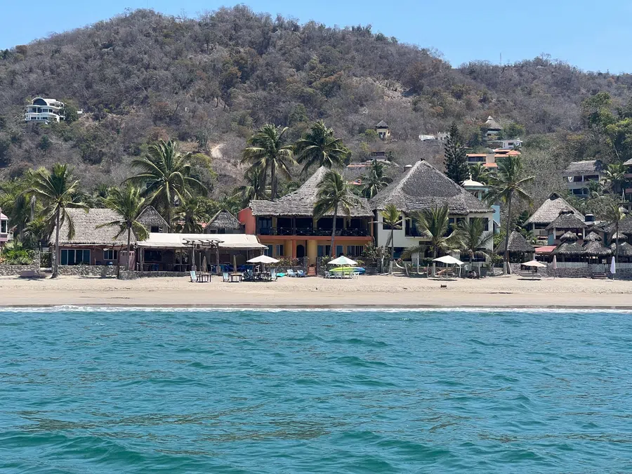 The village's beach, palapa roofs and hillside homes seen from just offshore.