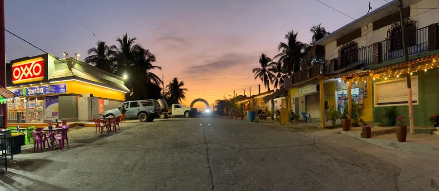 Shops and restaurants begin to glow as evening settles over the village's central street.