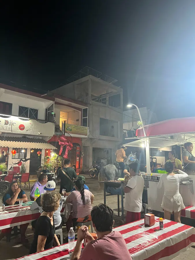 Busy outdoor tables and food stands bring La Manzanilla's streets to life after dark.