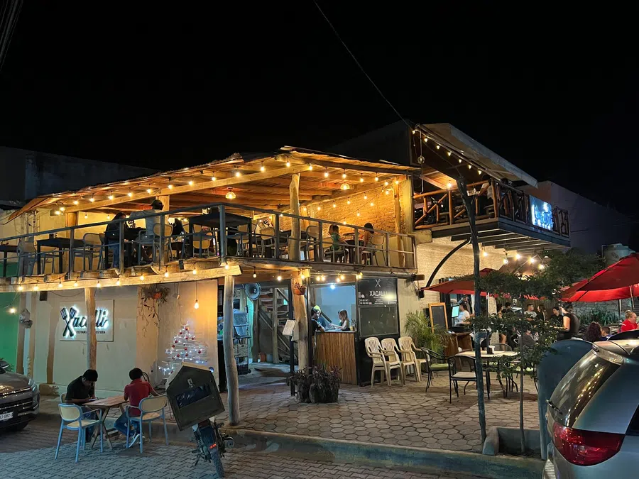 Warm string lights illuminate a lively two-level restaurant in the center of town.