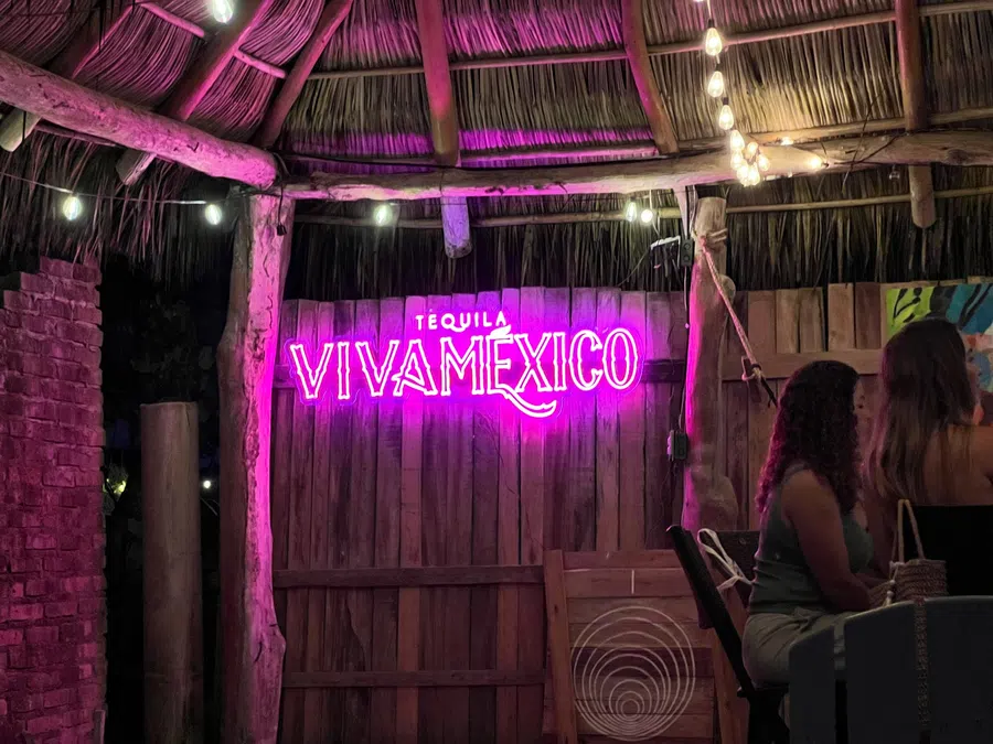 A small La Manzanilla venue glows with a vivid live-music sign and intimate evening atmosphere.