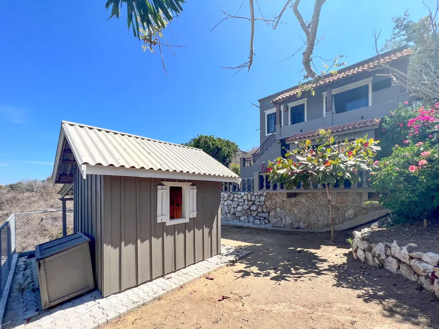 Compact outbuilding set into the landscaped hillside beside the residence.