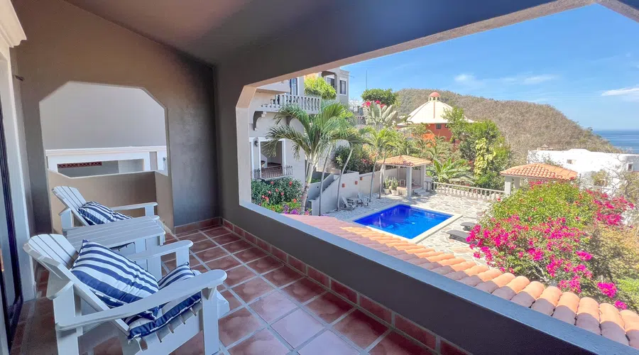 Shaded sitting terrace with a broad opening toward the pool, flowering gardens and surrounding hillside.