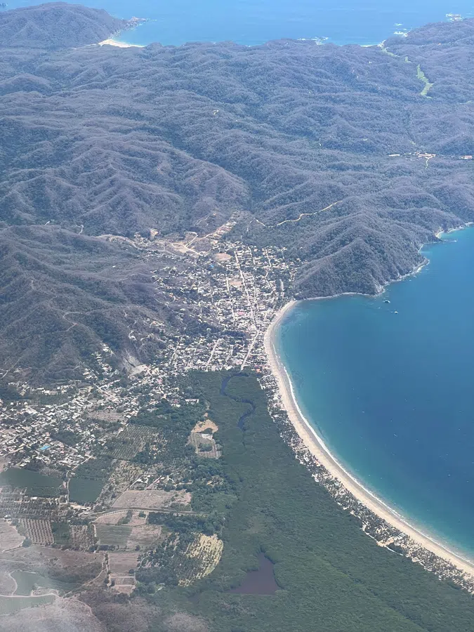 High aerial view tracing the bay, beach and dramatic Costalegre shoreline around La Manzanilla.