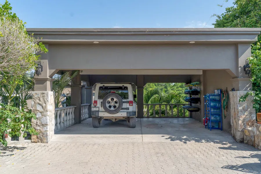 Covered 2-car carport and paved arrival area tucked into the property's tropical landscaping.