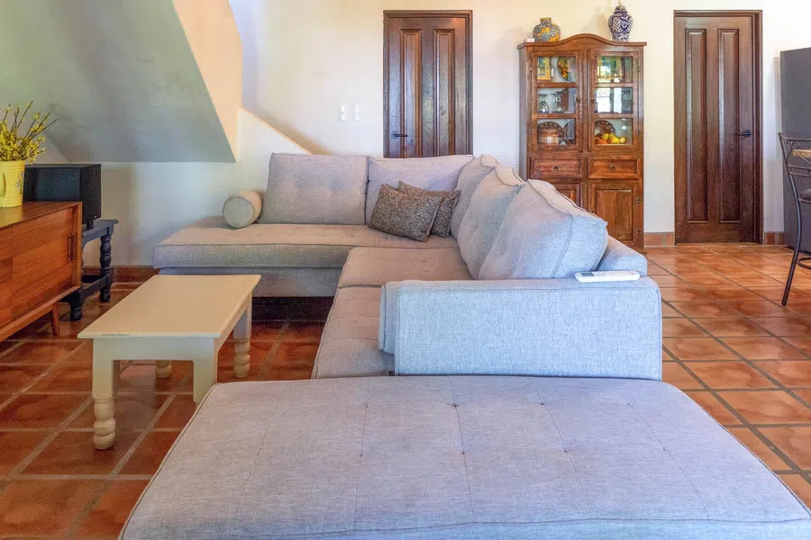 Comfortable living room with terracotta floors, pale walls and a large sectional seating area.