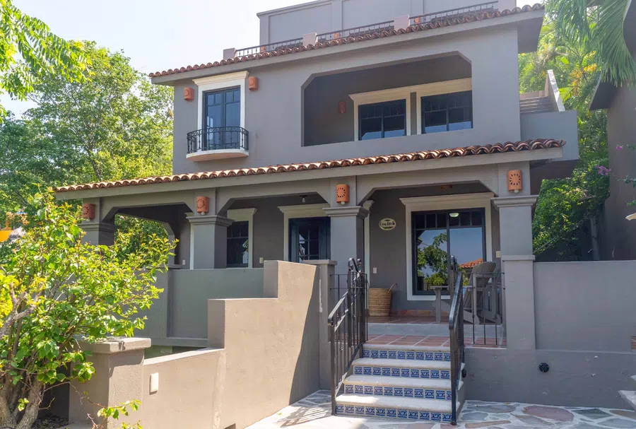 Exterior view of the independent 4BR guest residence with shaded balconies, tiled entry steps and garden surroundings.