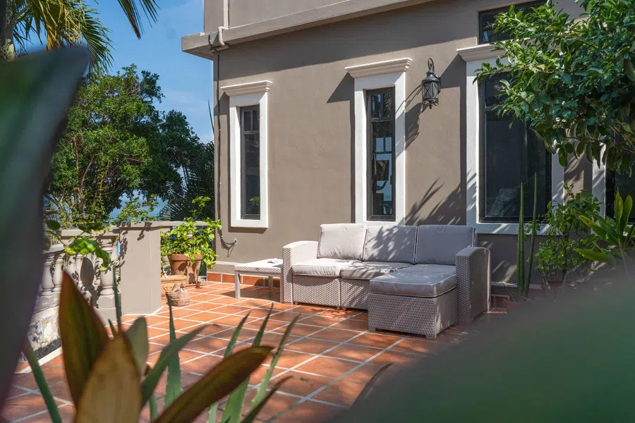 A quiet terracotta-tiled patio beside the residence, surrounded by mature tropical plants.