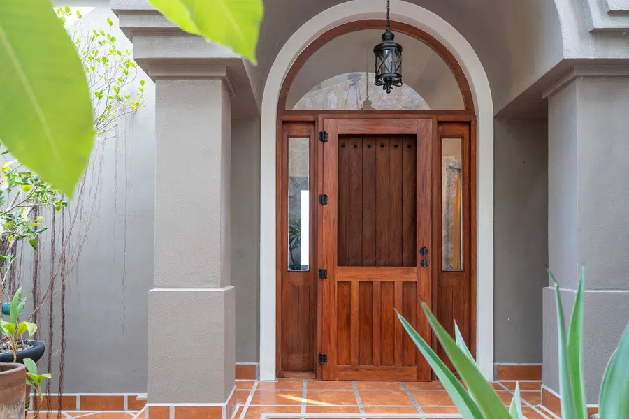 Arched entry and substantial wood door create a warm arrival to the main home.