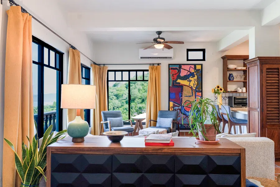 Bright living area with wraparound windows, terracotta floors and views through the tropical hillside.