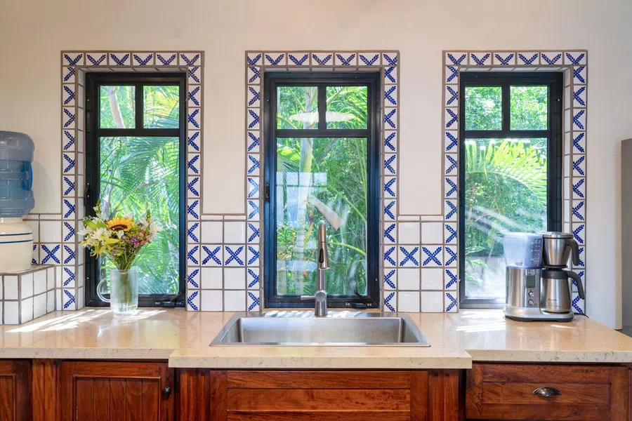 Three garden-facing windows brighten the main kitchen's handcrafted wood cabinetry and blue-and-white tile.