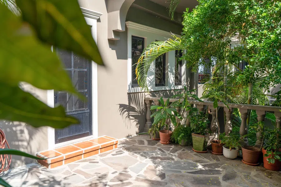 Stone and tile patio along the main residence is softened by abundant potted plants.