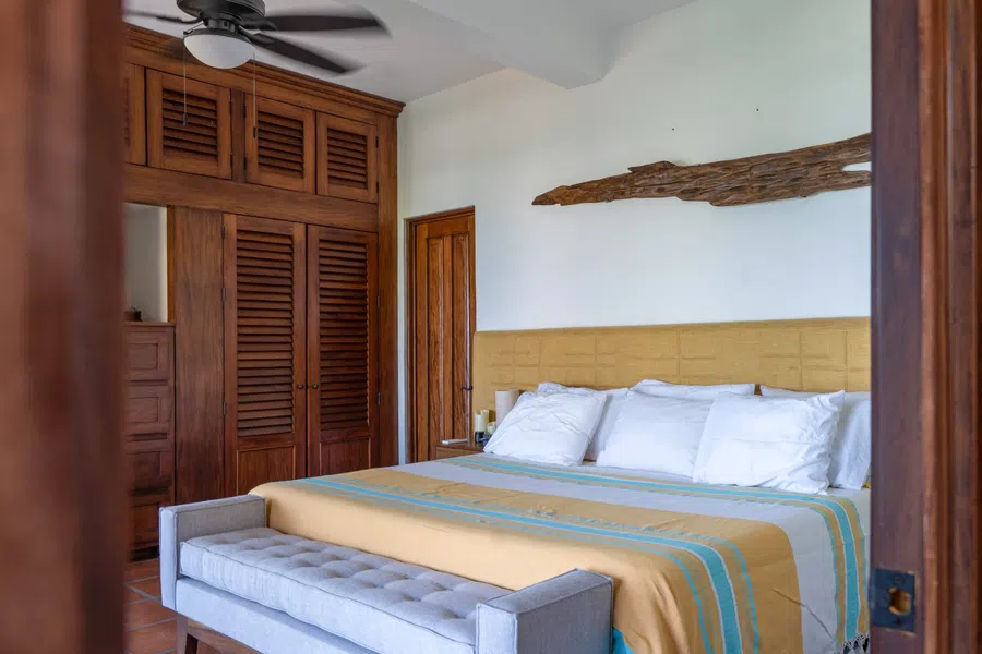 Spacious main-house bedroom with built-in wood closets and warm terracotta floors.