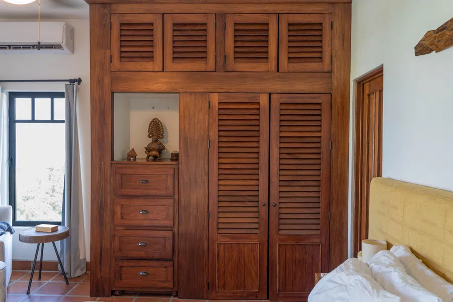 Handcrafted wood wardrobes and drawers provide substantial storage in the primary suite.