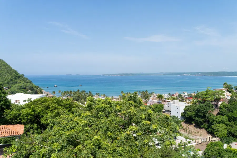 Panoramic Pacific view across treetops and the village below from third floor balcony.