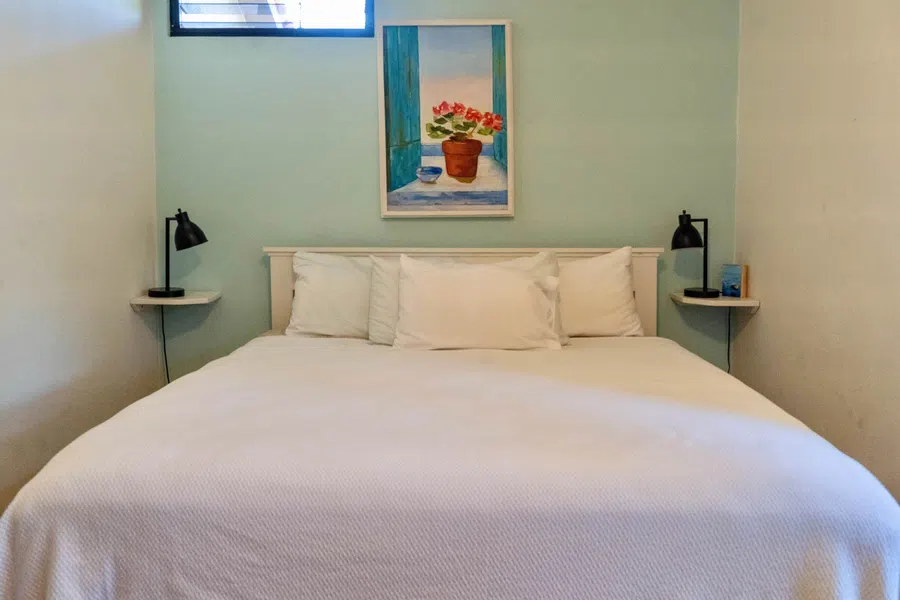 Simple, comfortable bedroom with king-sized bed and compact bedside shelves.