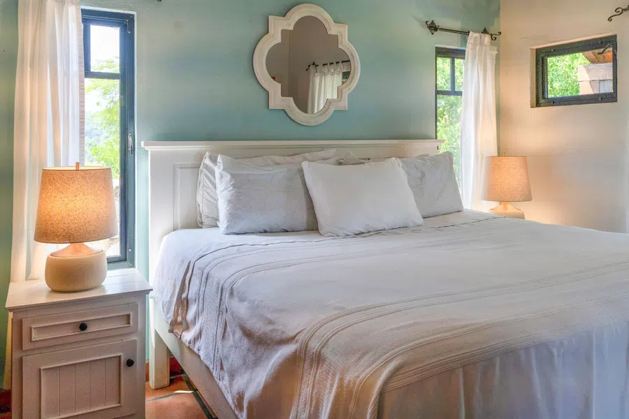 Air-conditioned bedroom with king-sized bed, abundant windows and a calm blue-and-white palette.